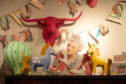 Pink cow head on wall with banners and other colorful toys.