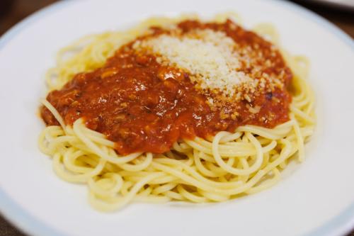 A plate of spaghetti topped with tomato sauce and sprinkled with grated cheese.