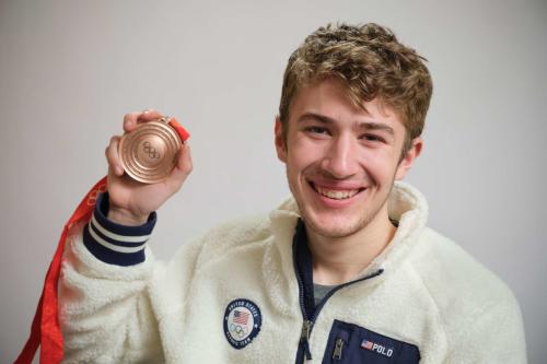 Man in sports gear holding up a bronze olympic medal