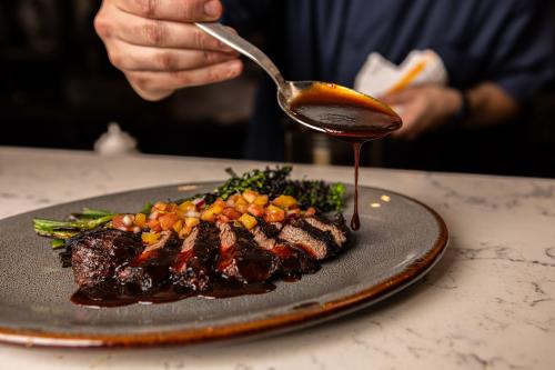 sauce being drizzled over steak