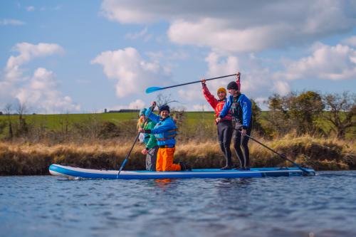 A group of paddleboarders sit and stand on their board in the river in the South Downs National Park