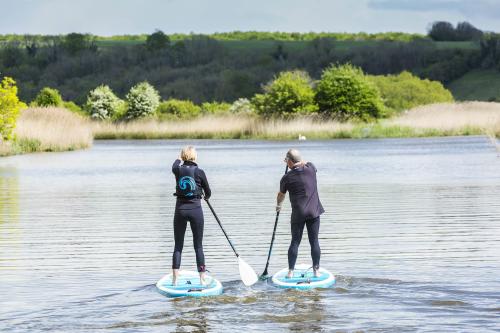 A couple stand up paddle boarding along a river in Sussex