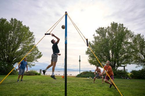 kids playing volleyball at waterfront park, jumping high and spreading joy