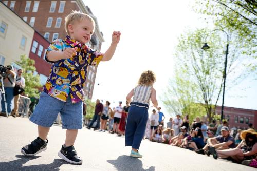 Toddler in bright shirt dancing on the streets of Burlington in the summer