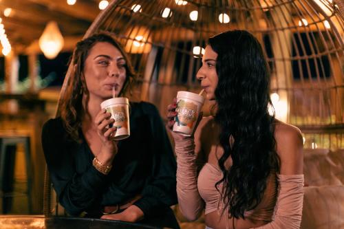 two girl friends enjoying orange crush drinks from the shack at night with hanging lights in the background