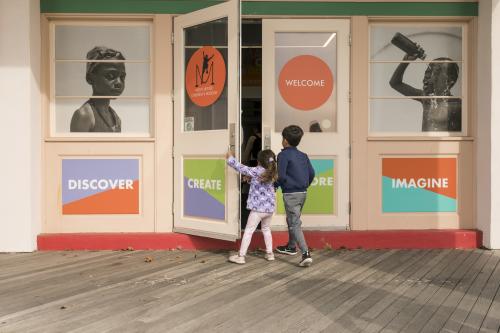 Two children are opening the door of the Westchester Children's Museum.
