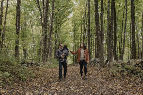 A family with two adults and one child walks down a leafy trail at Ward Pound Ridge Park.