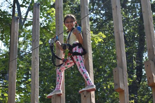 A girl is balanced on two wooden posts and is looking down at the camera.
