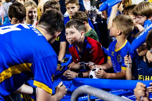 A group of fans look on excitedly as a Westchester Soccer player signs his autograph.