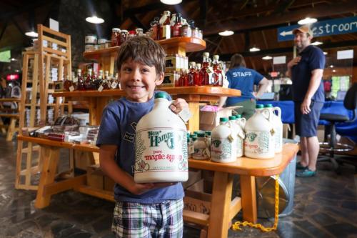 A young boy holds up a large jug of Maple Syrup at the gift shop at Polar Caves Park