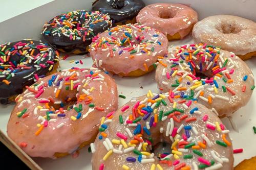 Box of Duck Donuts featuring chocolate, strawberry and iced frosting with sprinkles