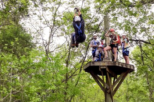 Young man ziplining through trees