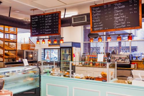 The inside of a bakery filled with many pastries and chalkboard menus