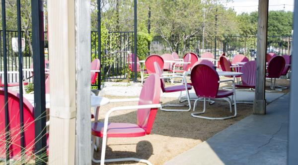 Outdoor patio with red and white metal chairs at Denton County Brewing Company in sunny weather