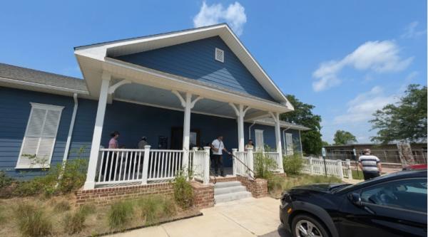 The Africatown Heritage House is a wooden house painted blue with a white trim porch and shutters.