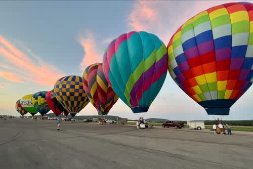 Hot air balloons in a line against a sunset