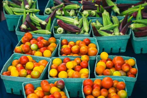 Bright red tomatoes and okra in blue containers.