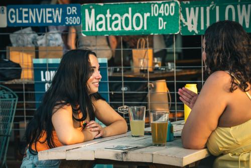 Two women taking sitting at a picnic table having a beer