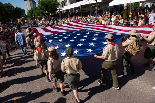 Scouts marching in Battle of Flowers Parade holding large American Flag