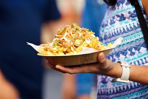 A close up shot of a tray piled with street food at an outdoor event
