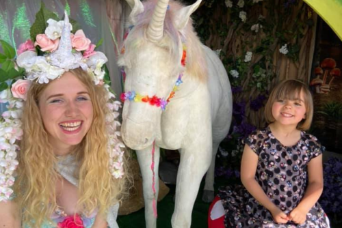 A woman and a young girl sitting next to a unicorn