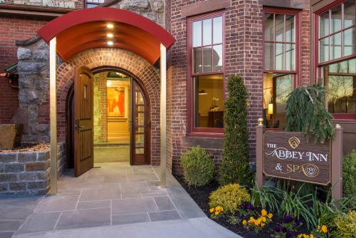 Entrance sign to The Abbey Inn & Spa. The entryway has an arched red canopy on the brick building.