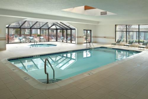 An indoor pool and whirlpool with windows and a skylight pouring light into the room.