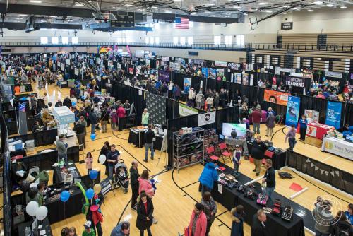 Large community expo taking place in recreational facility showcasing local businesses at exhibit booths