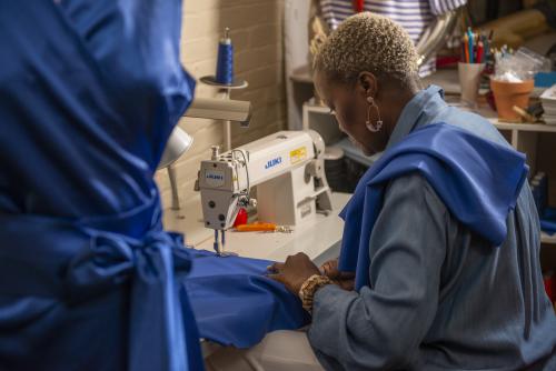 A woman using a sewing machine to make a piece of clothing
