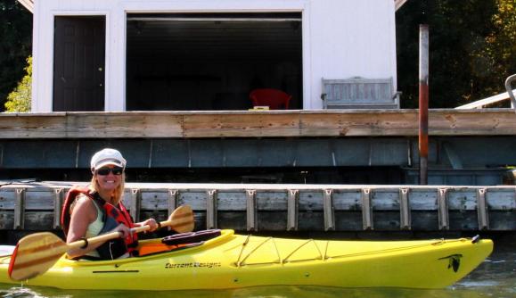 Woman kayaking in front of boathouse Woman kayaking in front of boathouse