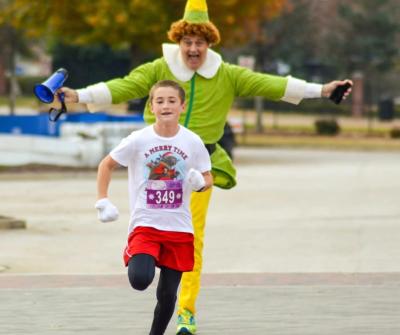 Kid running with Buddy the Elf behind him