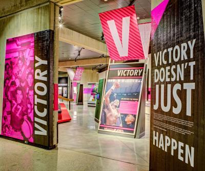 Hot pink signage with black and white text, large-scale images in the "Victory" section of "Ohio - Champion of Sports" exhibit at Ohio History Center
