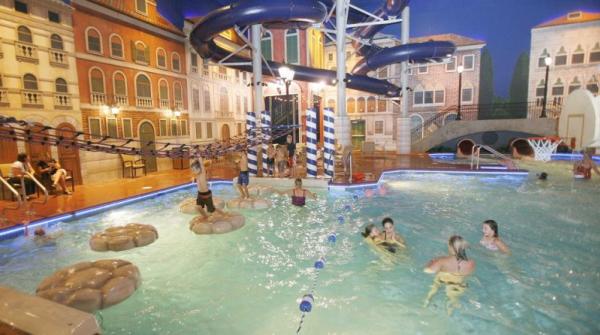 Kids and parents splashing in an indoor pool in a setting made to look like Italy at Venetian Waterpark at Holiday Inn, Maple Grove