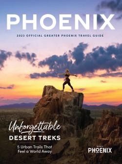A cover of the Visit Phoenix 2022-2023 Travel Guide, featuring a woman in a yoga pose on top of a mountain summit during sunrise.