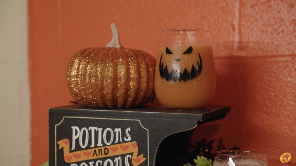 Image of a jack-o-lantern cup filled with an orange beer slushie, placed next to a sparkling orange pumpkin.