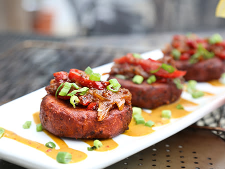 A barbecue hog cake sits on a plate with house made spicy queso dip at SoDoSoPa in Downtown Smithfield.