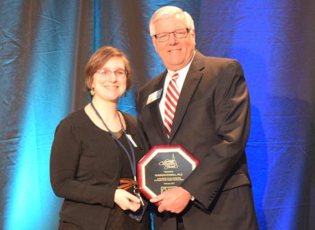 Shannon Schmoll, Ph. D. accepts her Community Champion Award from Jack Schripsema