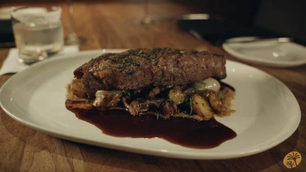 Image of a plate of steak served atop roasted vegetables.