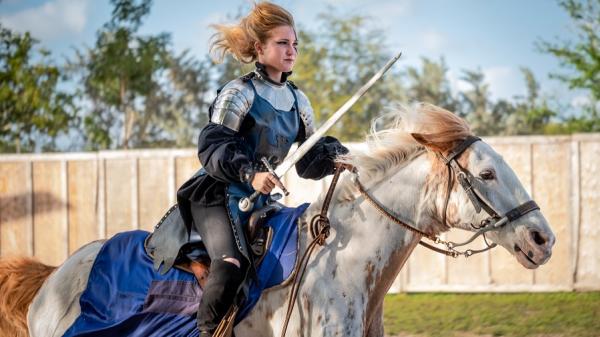 Young lady riding a horse with a sword - ready for battle