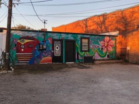 Back of Countdown 2 Escape building painted mural with red train, pink flower and longhorn with a teal or blue background.