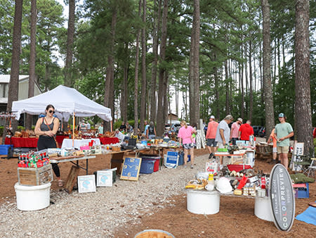 A woman views a variety of sale items on a table located in the woods at the Tobacco Farm Life Museum during the 301 Endless Yard Sale.