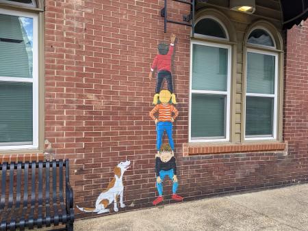 Children standing on each others shoulders with dog mural located in Selma, NC.