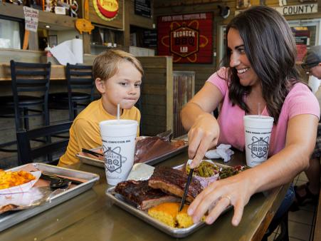 Table of food at Redneck BBQ Lab with mother and son cutting cornbread