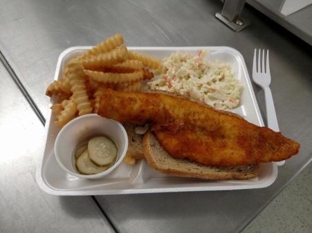fried fish sandwich with side of French fries, Cole slaw, and pickles