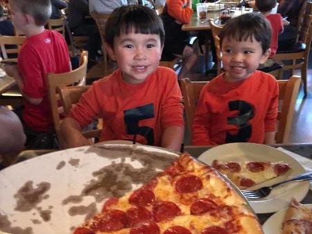 two kids smiling while eating pepperoni pizza at deweys