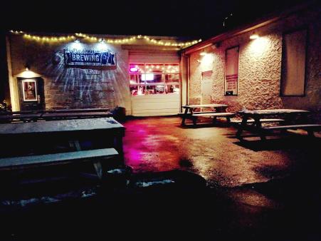interior shot of darnkess brewery in bellevue, ky.  picnic tables, lights, garage door, sign painted on brick