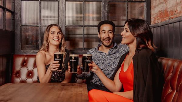 Group of three people enjoying pints of Guinness in White's Tavern & BeerHall Belfast.