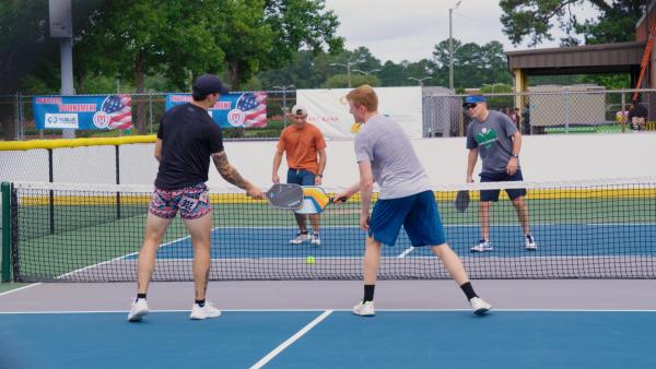 Four players playing pickleball together during a reunion at an outdoor court in Fayetteville, North Carolina