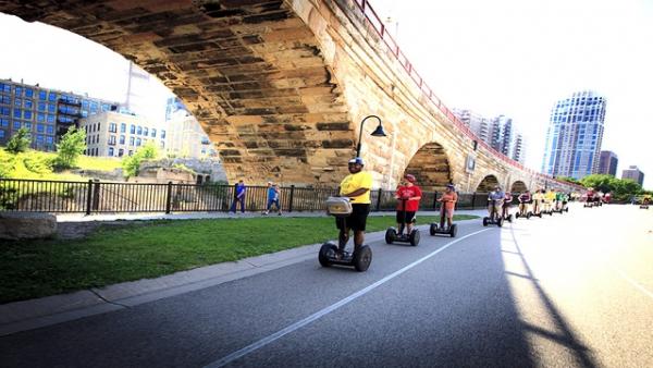 People riding segways under the Stone Arch Bridge