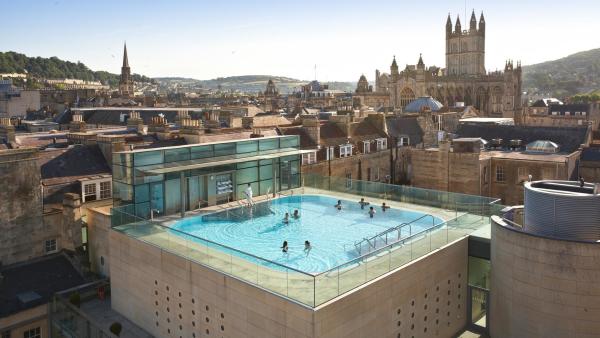 Eight people enjoy the peace of a rooftop pool at a spa in Bath, England